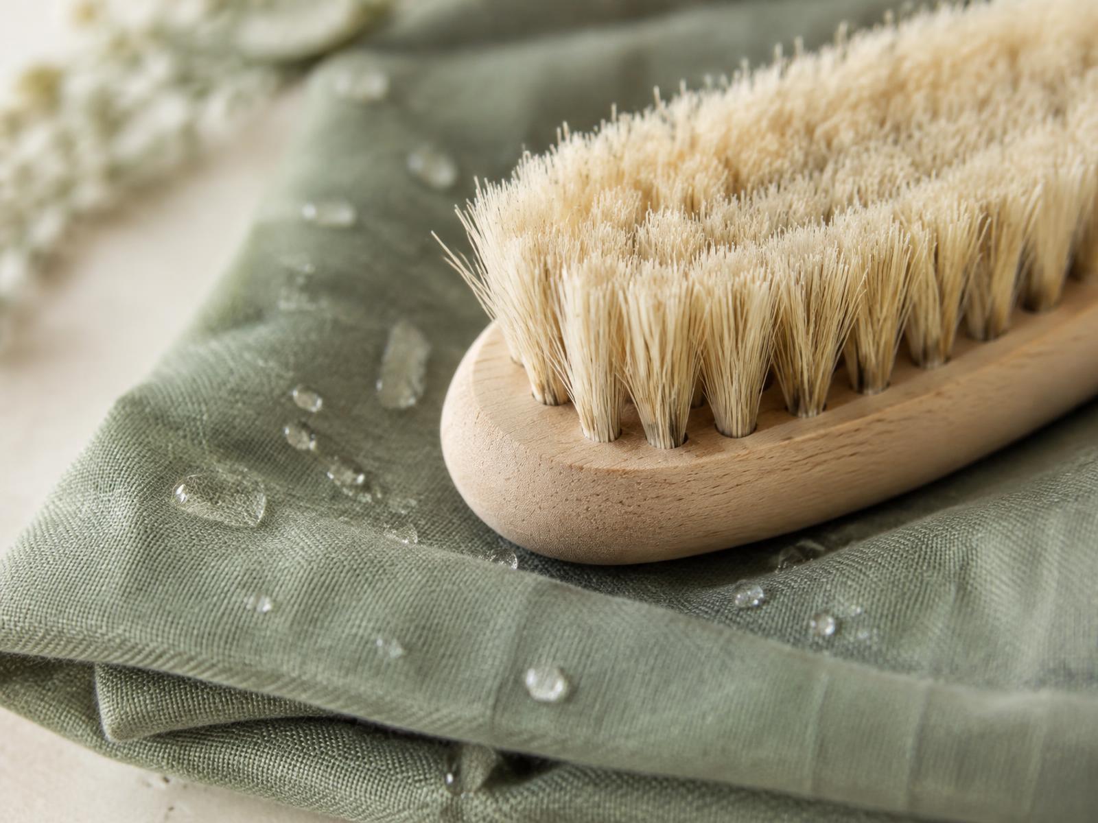 Close-up of a natural bristle brush on folded sage linen