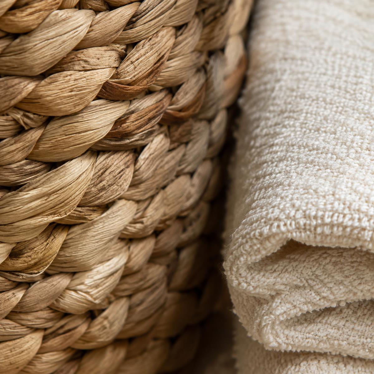 Close-up of woven seagrass beside a folded cream towel